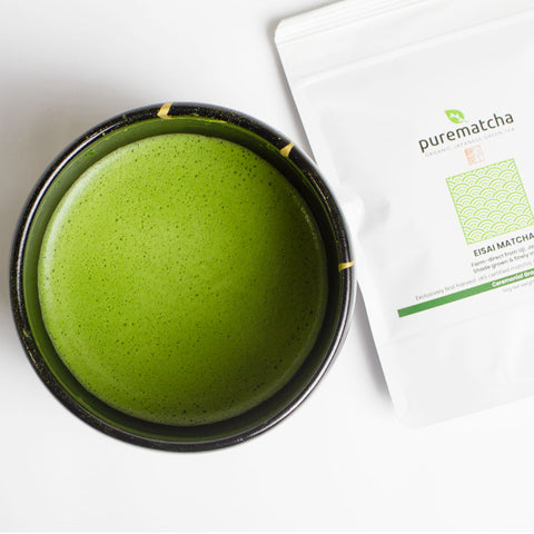 Green matcha tea in a bowl with a package of purematcha on a white background