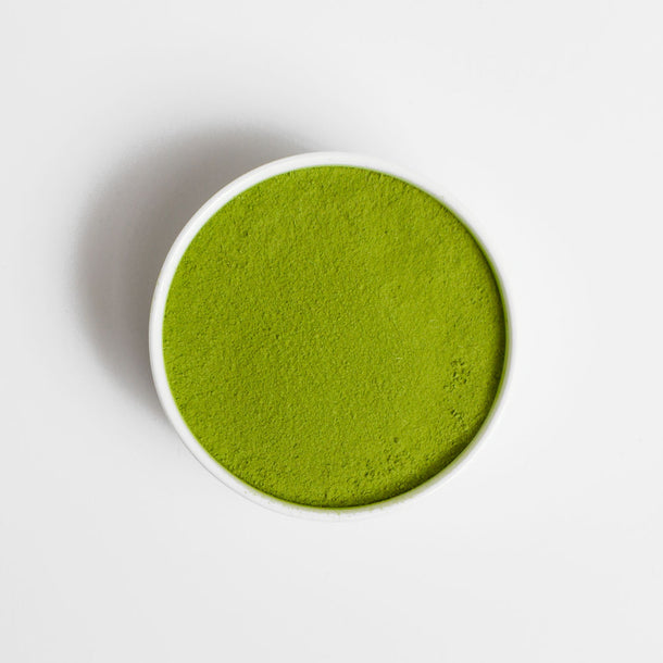 Green powder in a white container on a white background
