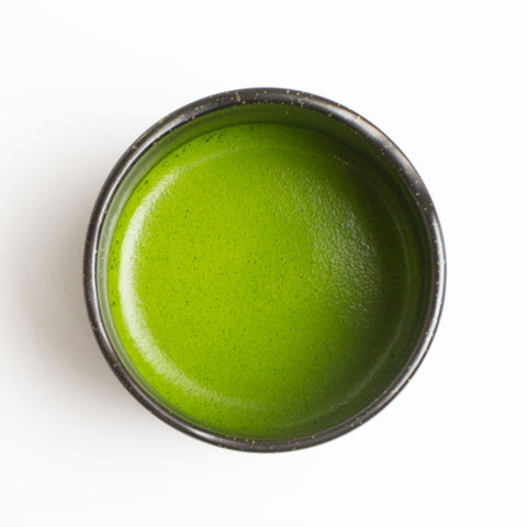 Chawan filled with creamy organic ceremonial grade matcha in a bowl on a white background