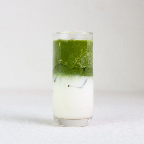 Glass with a layered drink of green and white on a white background