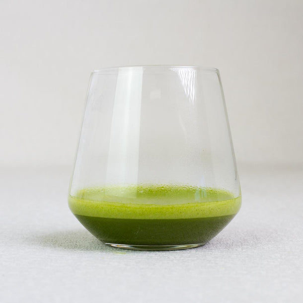 Clear glass with green matcha tea on a white background