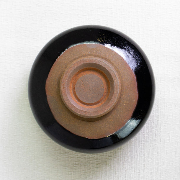 Ceramic dish with black exterior and brown interior on a white background