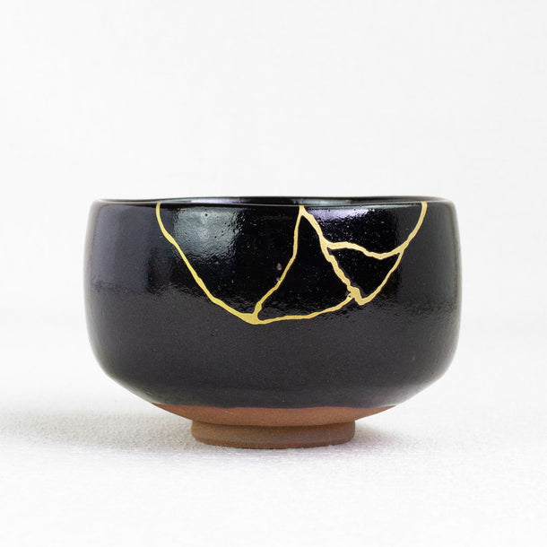 Black ceramic bowl with gold裂纹 design on a white background