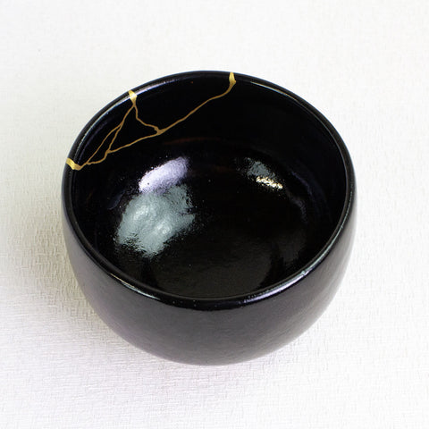 Black ceramic bowl with gold accents on a white background