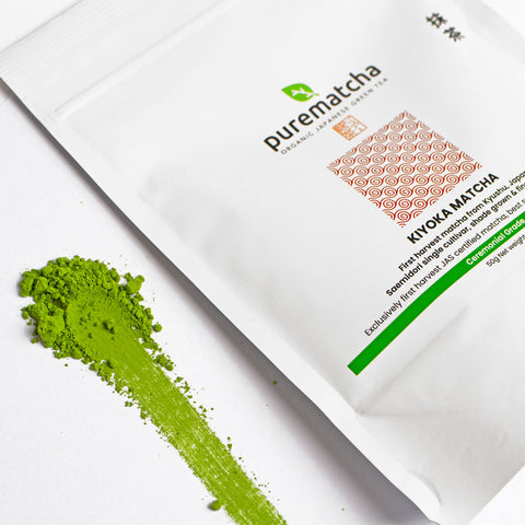 Purematcha green tea powder packaging with a scoop of green powder on a white background