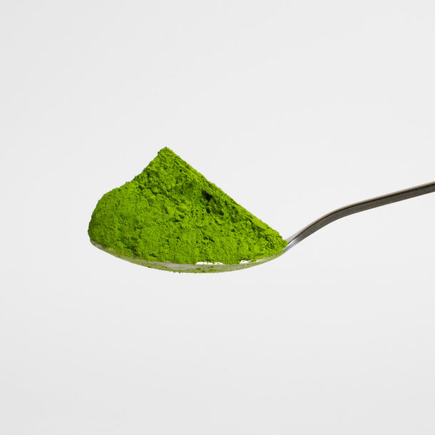 Spoonful of green powder on a white background