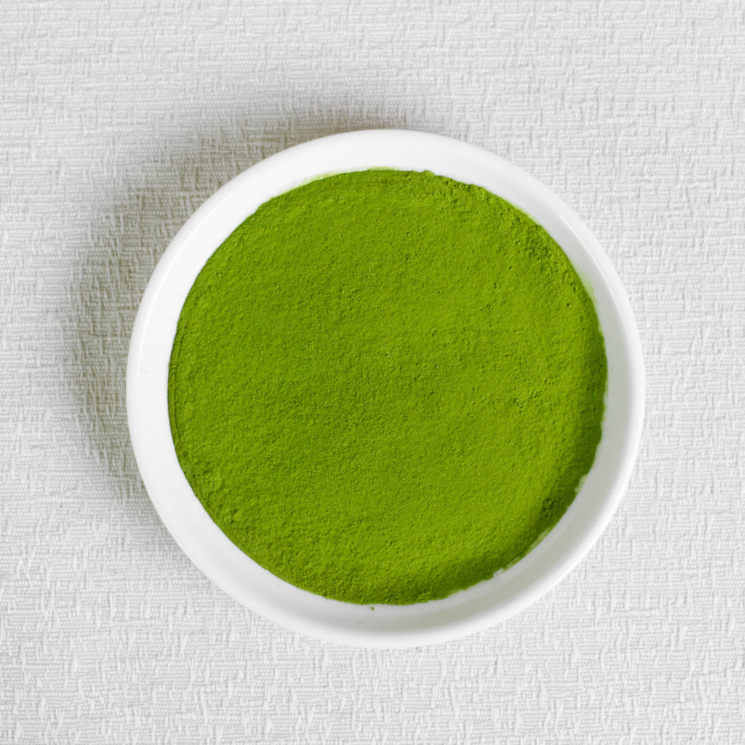 Ceremonial Grade Organic Matcha Green powder in a white bowl on a textured white background