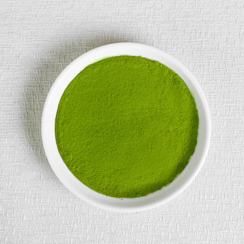 Ceremonial Grade Organic Matcha Green powder in a white bowl on a textured white background