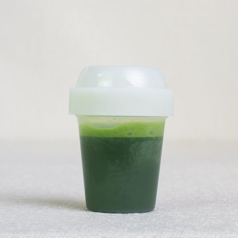Matcha Mini Shaker Bottle filled with matcha tea on a table with white background