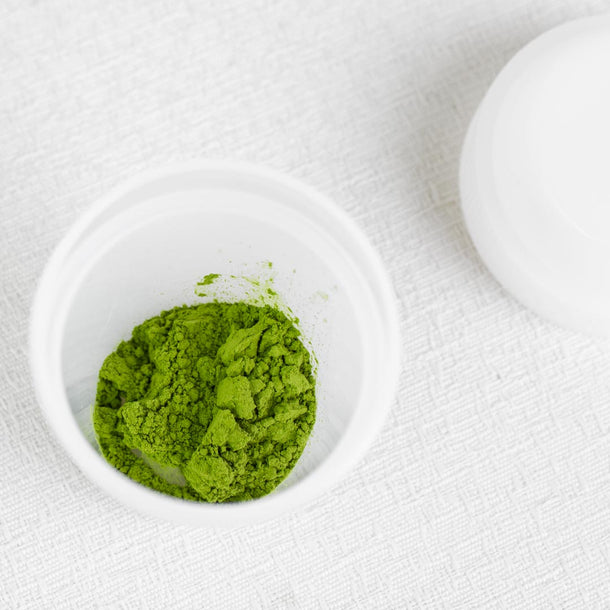 Green powder in the matcha mini shaker bottle on a white background