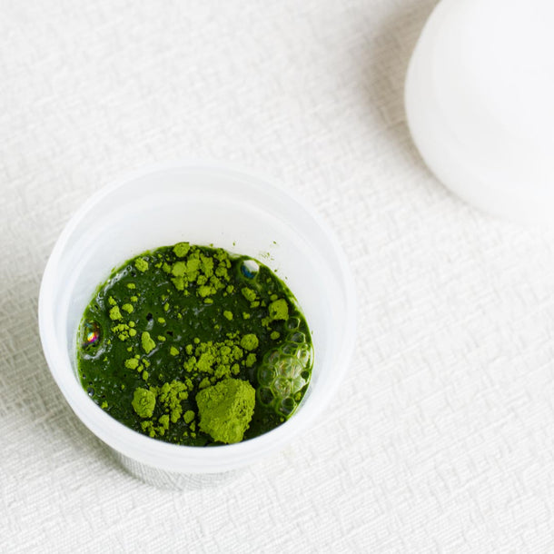 Green powder in a matcha mini shaker bottle on a white background