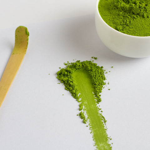 Deep steamed sencha green tea powder with a spoon and bowl on a white background