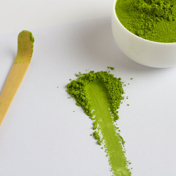 Deep steamed sencha green tea powder with a spoon and bowl on a white background