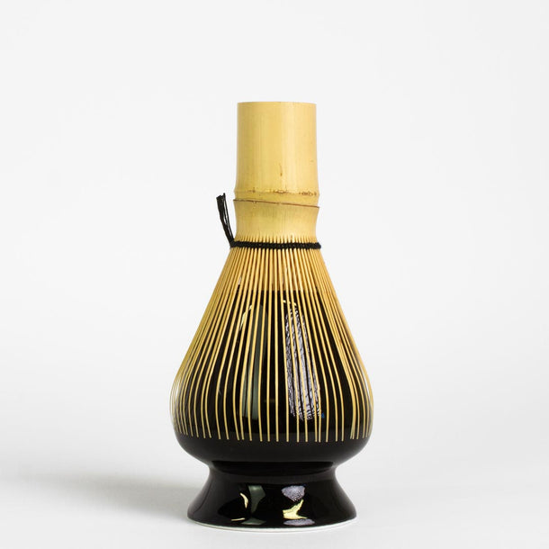 Japanese matcha whisk resting on black whisk stand