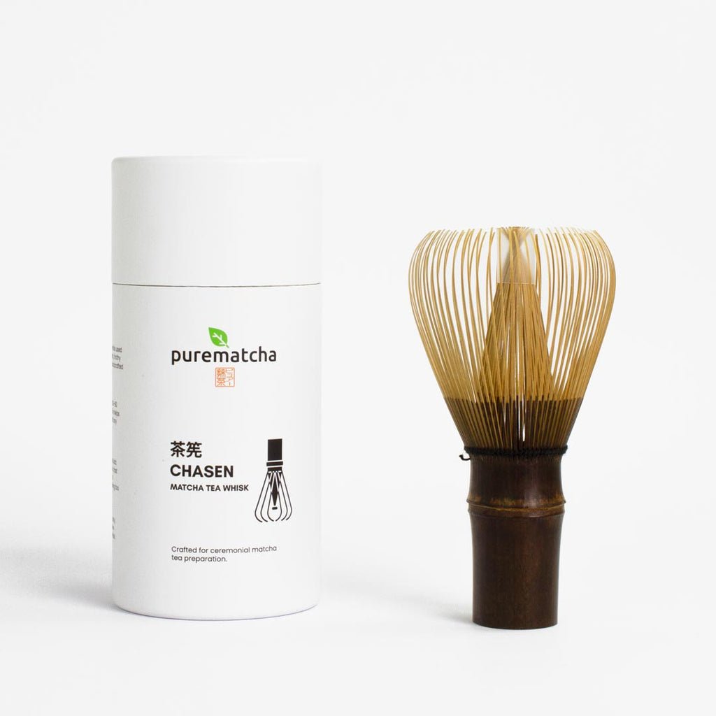 White container labeled 'purematcha' with a bamboo whisk on a white background